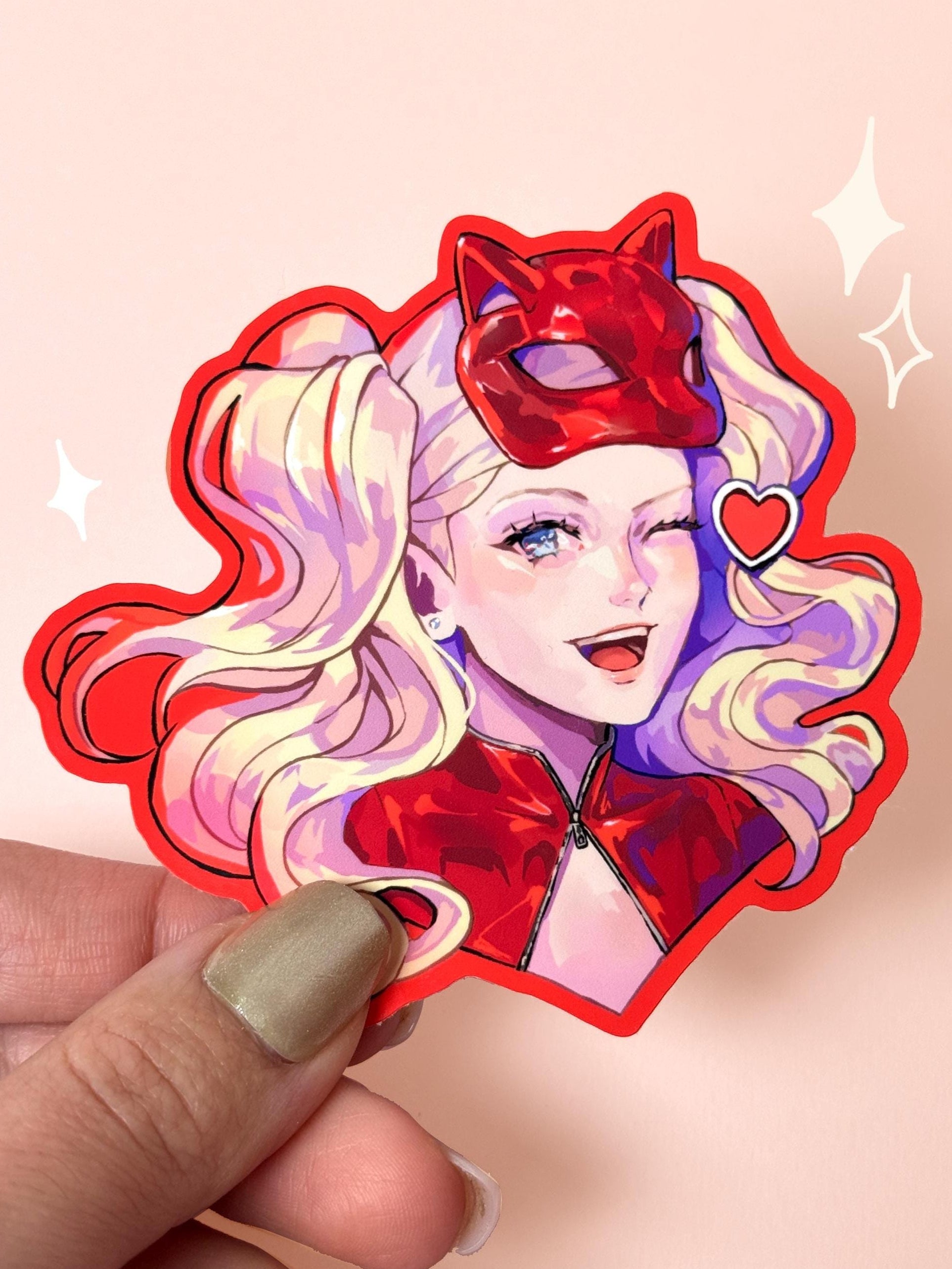 Die-cut vinyl sticker of Ann Takamaki (Panther) from Persona 5, winking and smiling in her red Phantom Thief catsuit and cat mask, held between fingers against a peach background.