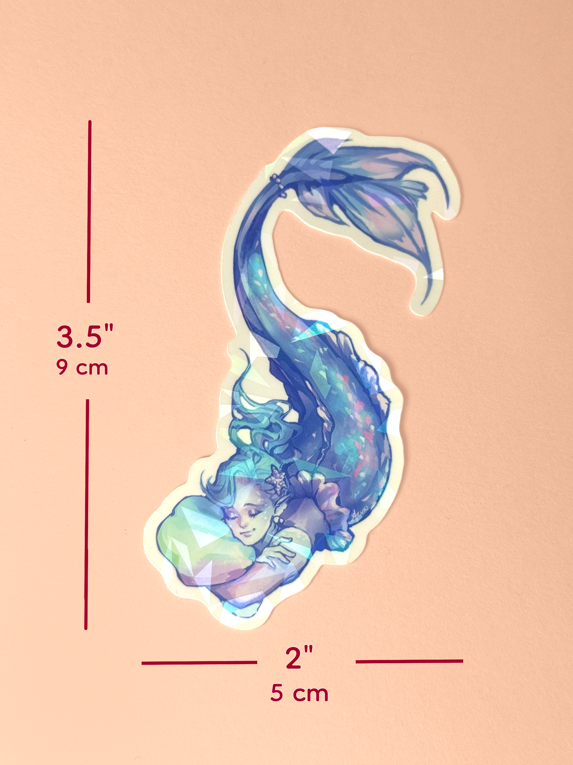 The holographic mermaid sticker measures 3.5 inches tall and 2 inches wide.