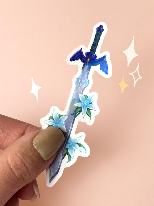 Die-cut holographic vinyl sticker of the Master Sword from The Legend of Zelda, with the blade pointing downward through clusters of pale blue Silent Princess flowers, held between fingers against a peach background.