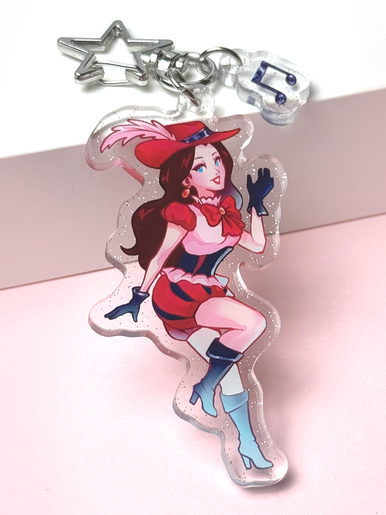 Glitter acrylic keychain of Pauline from Super Mario reimagined as a bard — long dark red hair, a red feathered hat, red dress with bow, and blue gloves and boots, with a star-shaped clasp and a music-note charm.