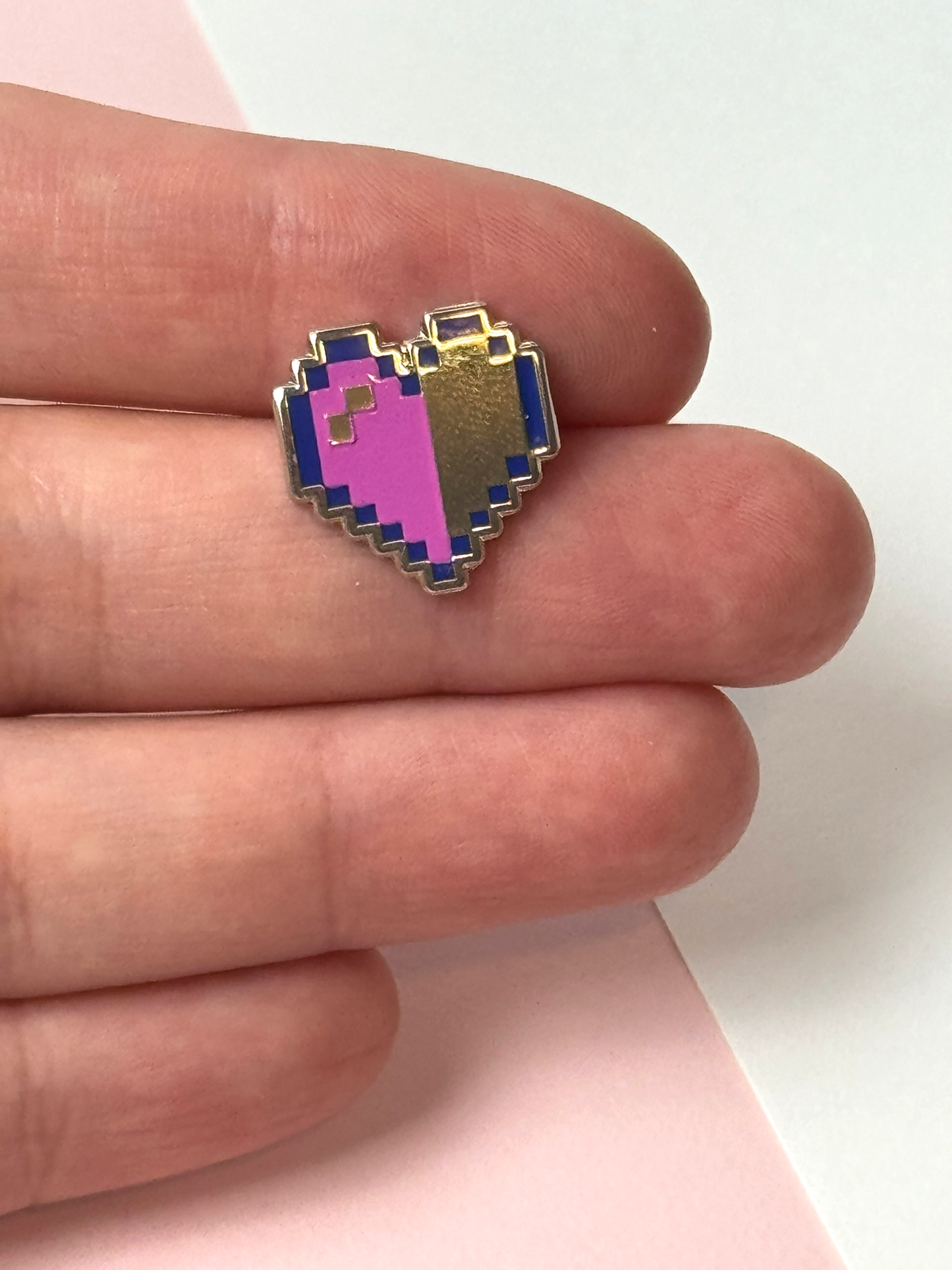 The pixel heart pin held in hand.