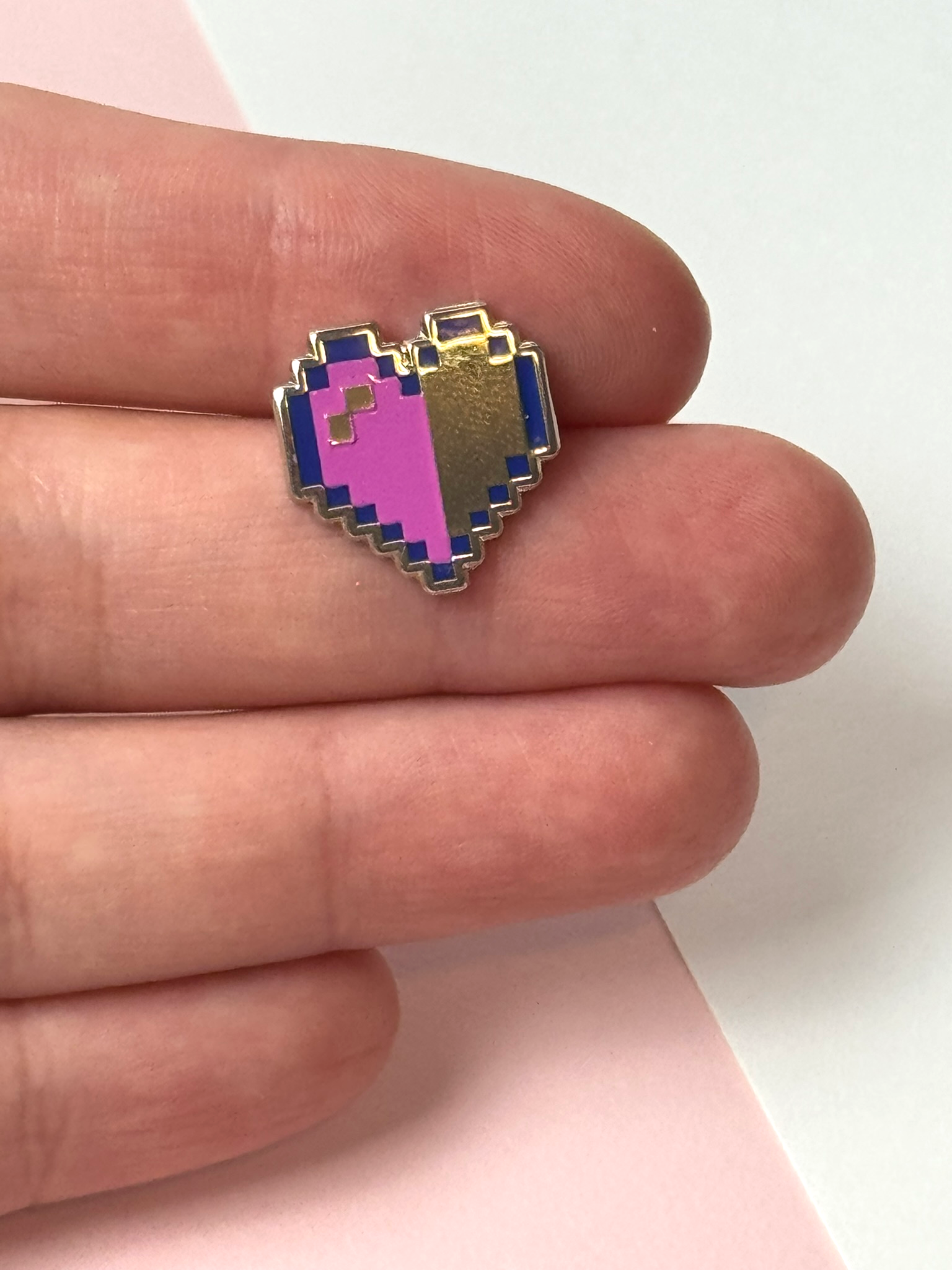 The pixel heart pin held in hand.