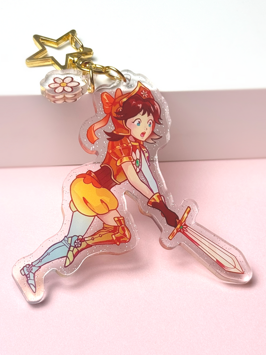 Glitter acrylic keychain of Princess Daisy from Super Mario reimagined as a knight — brown hair with an orange bow, orange-and-gold armor, holding a sword in a battle stance, with a star-shaped clasp and a flower charm.