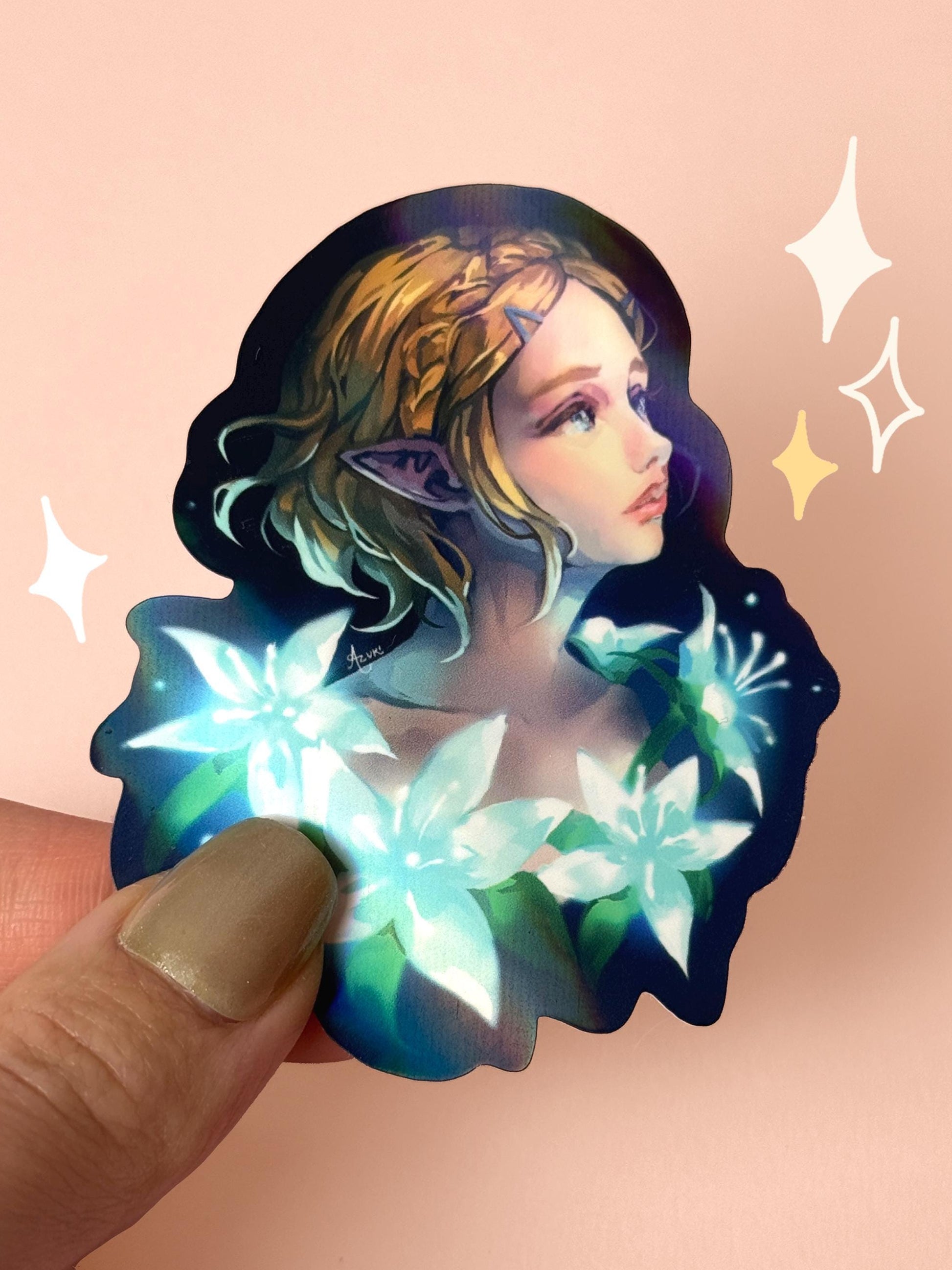 Die-cut holographic vinyl sticker of Princess Zelda from The Legend of Zelda, with braided blonde hair, pointed Hylian ears, and glowing Silent Princess flowers on a dark background, held between fingers against a peach background.