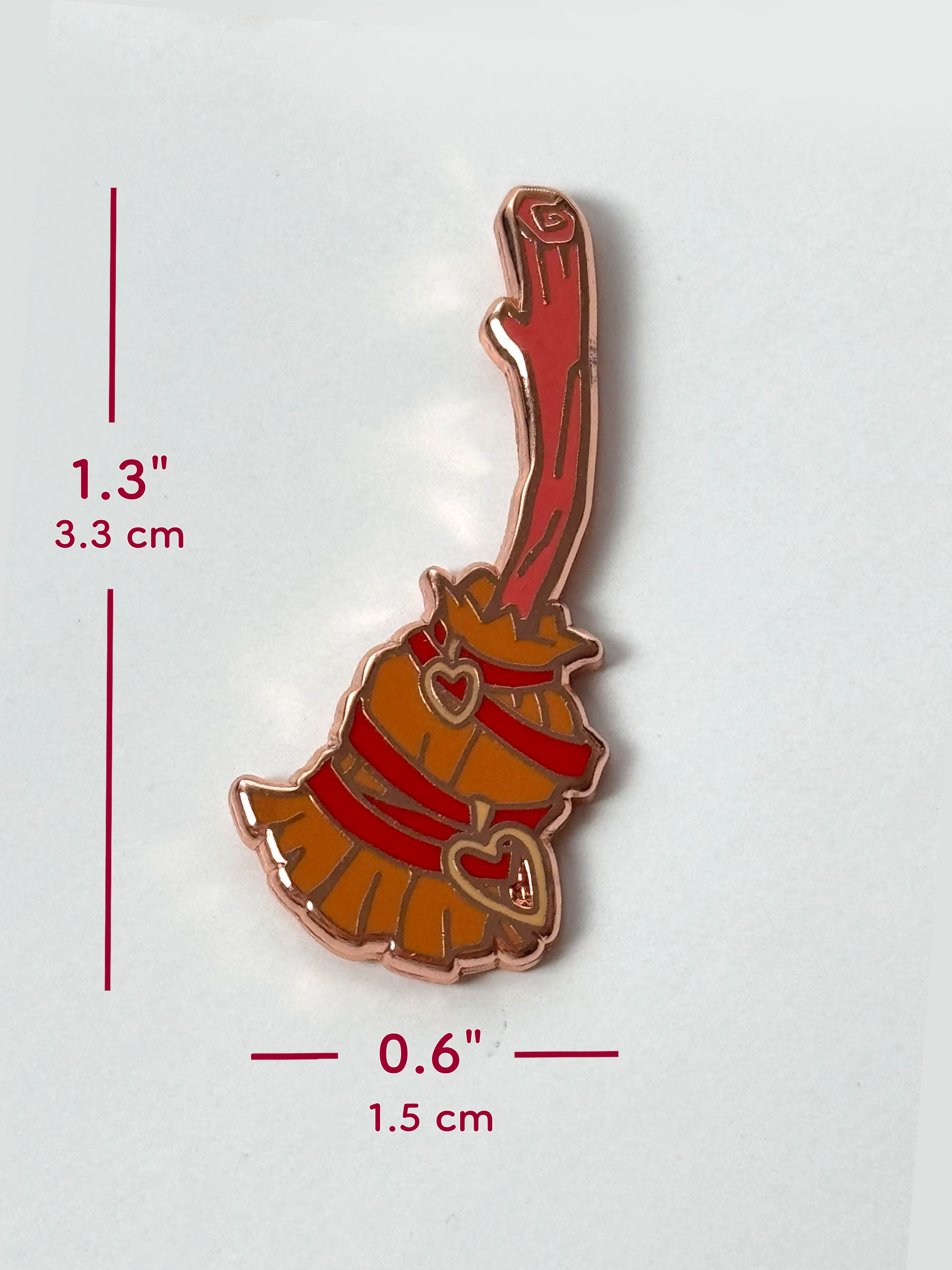 The witch broom pin measures 1.3 inches tall and 0.6 inches wide.