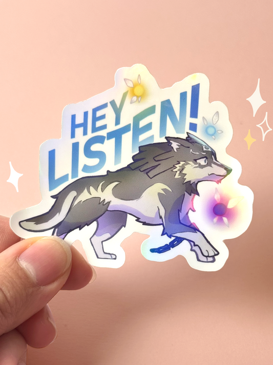 Die-cut holographic vinyl sticker of Wolf Link from The Legend of Zelda: Twilight Princess, a grey wolf in mid-step with a broken chain on his leg, surrounded by Navi-style fairies and bold blue "Hey Listen!" text, held between fingers against a peach background.