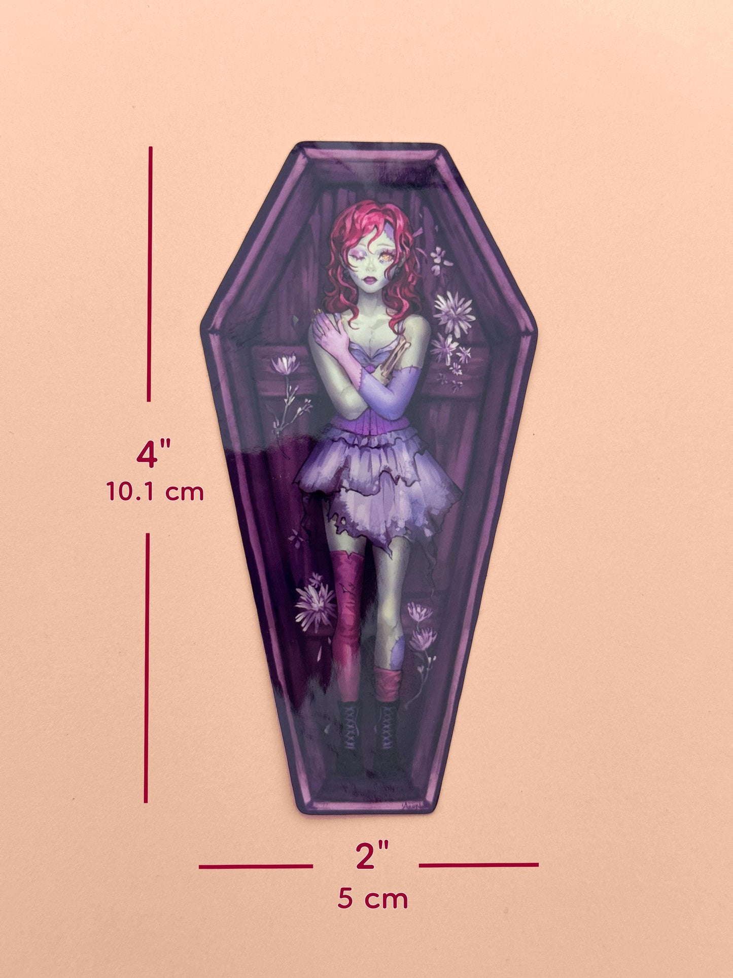 The zombie coffin girl sticker measures 4 inches tall and 2 inches wide.