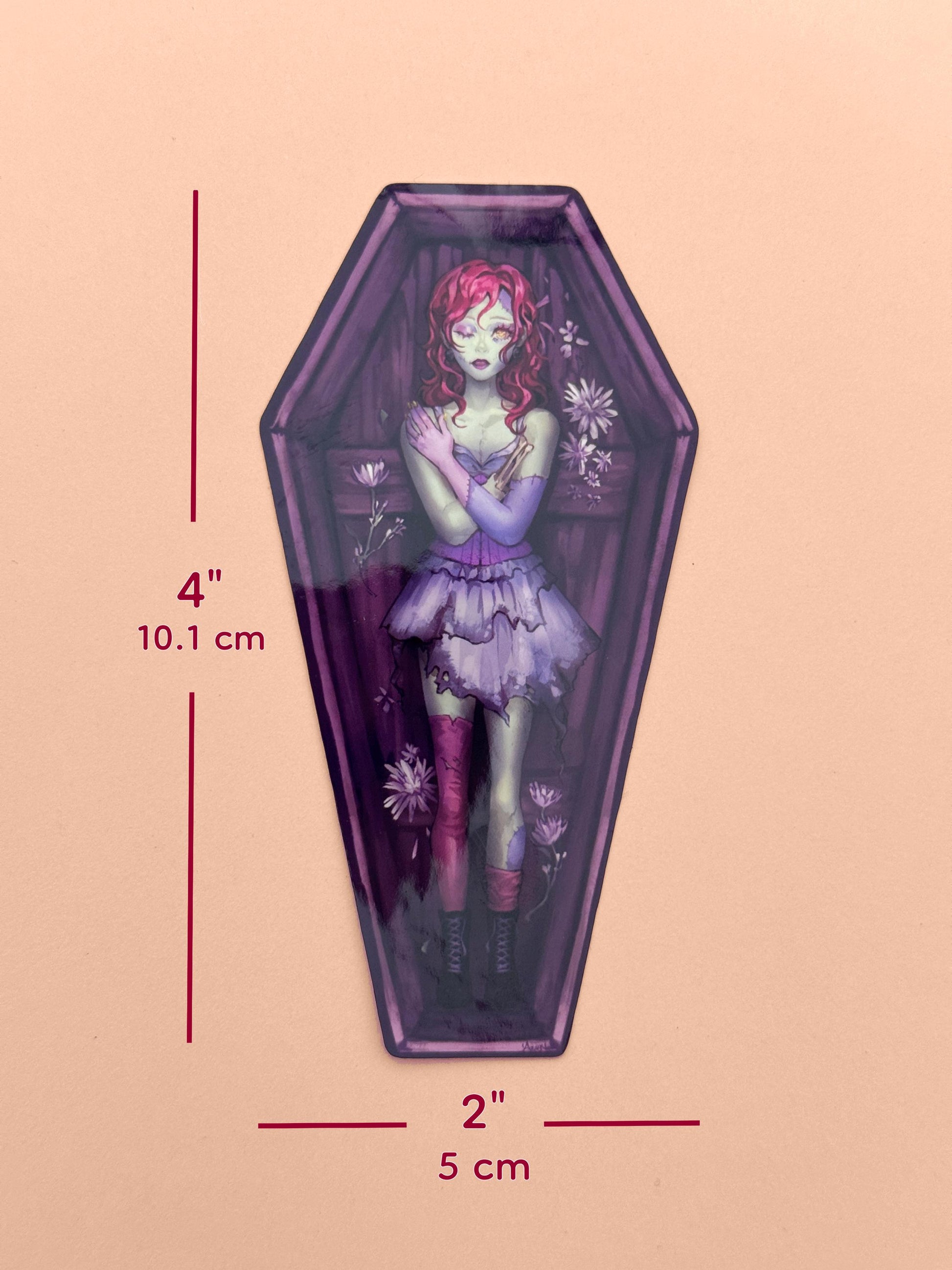 The zombie coffin girl sticker measures 4 inches tall and 2 inches wide.